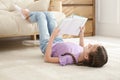 Cute little girl reading book on floor Royalty Free Stock Photo