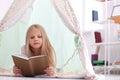 Cute little girl reading book in hovel at home