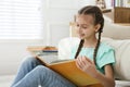 Cute little girl reading book near sofa at home Royalty Free Stock Photo