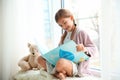 Cute little girl reading book near window Royalty Free Stock Photo