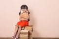 Cute little girl reading book sitting on pile of books. Royalty Free Stock Photo