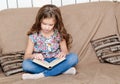 Cute little girl is reading the book on the sofa Royalty Free Stock Photo