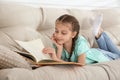 Cute little girl reading book on sofa Royalty Free Stock Photo