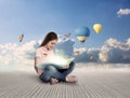 Cute girl reading magic book. Picturesque view of blue sky and air ballons on background Royalty Free Stock Photo