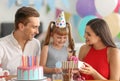 Cute little girl receiving birthday gift from parents at party Royalty Free Stock Photo