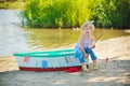 A cute little girl in a red bathing suit standing on the beach against the backdrop of boats Royalty Free Stock Photo