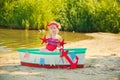 A cute little girl in a red bathing suit standing on the beach against the backdrop of boats Royalty Free Stock Photo