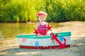 A cute little girl in a red bathing suit standing on the beach against the backdrop of boats Royalty Free Stock Photo