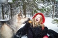 Cute little girl in red cap or hat and black coat with basket of green fir branches treats with a pie of big dog