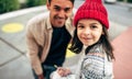 Cute little girl in red cap is sitting outdoor and drawing with her dad. Father enjoying the time together with his child outside Royalty Free Stock Photo