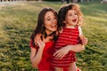 Cute little girl in red dress having fun in park with mom. Outdoor photo of blithesome woman playing