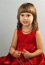 Cute little girl in a red dress with necklace in h Royalty Free Stock Photo