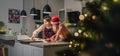 Cute little girl in red Santa hat with mother making homemade Christmas gingerbread cookies using cookie cutters together in home Royalty Free Stock Photo
