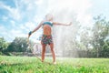 Cute little girl refresh herself from garden watering hose