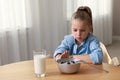 Cute little girl refusing to eat her breakfast at home, space for text Royalty Free Stock Photo