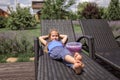 A cute little girl relaxing on the chaise longue at green garden outside, home feeling Royalty Free Stock Photo