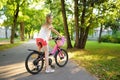 Cute little girl riding a bike in a city park on sunny summer day. Royalty Free Stock Photo