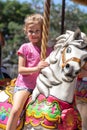 Cute little girl riding on a carousel in an amusement park in the summer. Royalty Free Stock Photo