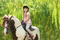 Cute little girl riding pony in green Royalty Free Stock Photo