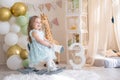 Cute little girl riding a toy wooden rocking horse at home at her birthday Royalty Free Stock Photo