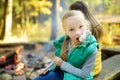 Cute little girl roasting marshmallows on stick at bonfire. Child having fun at camp fire. Camping with children in fall forest.