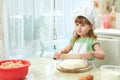 Cute little girl rolls out dough with a rolling pin in kitchen. She`s assistant Royalty Free Stock Photo