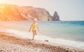 Cute little girl running along the seashore against a clear blue sea and rejoices in the rays of the summer sun Royalty Free Stock Photo