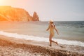 Cute little girl running along the seashore against a clear blue sea and rejoices in the rays of the summer sun Royalty Free Stock Photo
