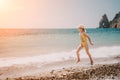 Cute little girl running along the seashore against a clear blue sea and rejoices in the rays of the summer sun Royalty Free Stock Photo