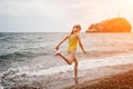 Cute little girl running along the seashore against a clear blue sea and rejoices in the rays of the summer sun Royalty Free Stock Photo