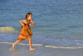 Cute little girl running on sandy beach in sunset Royalty Free Stock Photo