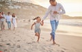 Cute little girl running hand in hand with her mixed race dad on the beach. A daughter and her father holding hands Royalty Free Stock Photo