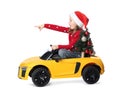 Cute little girl in Santa hat with Christmas tree driving children`s electric toy car on white background Royalty Free Stock Photo