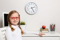 Cute little girl schoolgirl with glasses sits at a table. Close-up child on the background of the schoolgirl workplace Royalty Free Stock Photo