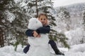 Cute Little girl sculpts snowman in winter Park.