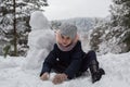 Little girl sculpts snowman in winter snowy Park. Royalty Free Stock Photo