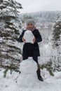 Cute girl sculpts snowman in winter snowy Park. Royalty Free Stock Photo