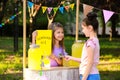 Cute little girl selling natural lemonade to kid in park