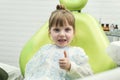 Cute little girl showing thumb up sign at dentist`s office clin