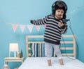 Cute little girl sing a song with smartphone in her bedroom, Happy asian child little girl listening the music with headphone on Royalty Free Stock Photo