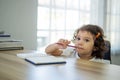 Cute little girl sit at desk at home doing homework, reading, writing and painting. Children paint. Kids draw. Preschooler with Royalty Free Stock Photo
