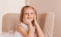 Cute little girl sits on a chair in a light room