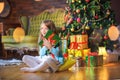 Cute little girl sits on the floor in the room near the festive Christmas tree Royalty Free Stock Photo
