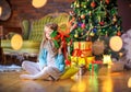 Cute little girl sits on the floor in the room near the festive Christmas tree Royalty Free Stock Photo