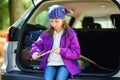 Cute little girl sitting in a car and using a pocket knife to whittle a hiking stick Royalty Free Stock Photo