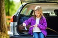 Cute little girl sitting in a car and using a pocket knife to whittle a hiking stick Royalty Free Stock Photo