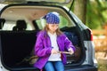 Cute little girl sitting in a car and using a pocket knife to whittle a hiking stick Royalty Free Stock Photo