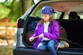 Cute little girl sitting in a car and using a pocket knife to whittle a hiking stick Royalty Free Stock Photo