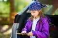 Cute little girl sitting in a car and using a pocket knife to whittle a hiking stick Royalty Free Stock Photo