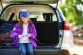 Cute little girl sitting in a car and using a pocket knife to whittle a hiking stick Royalty Free Stock Photo